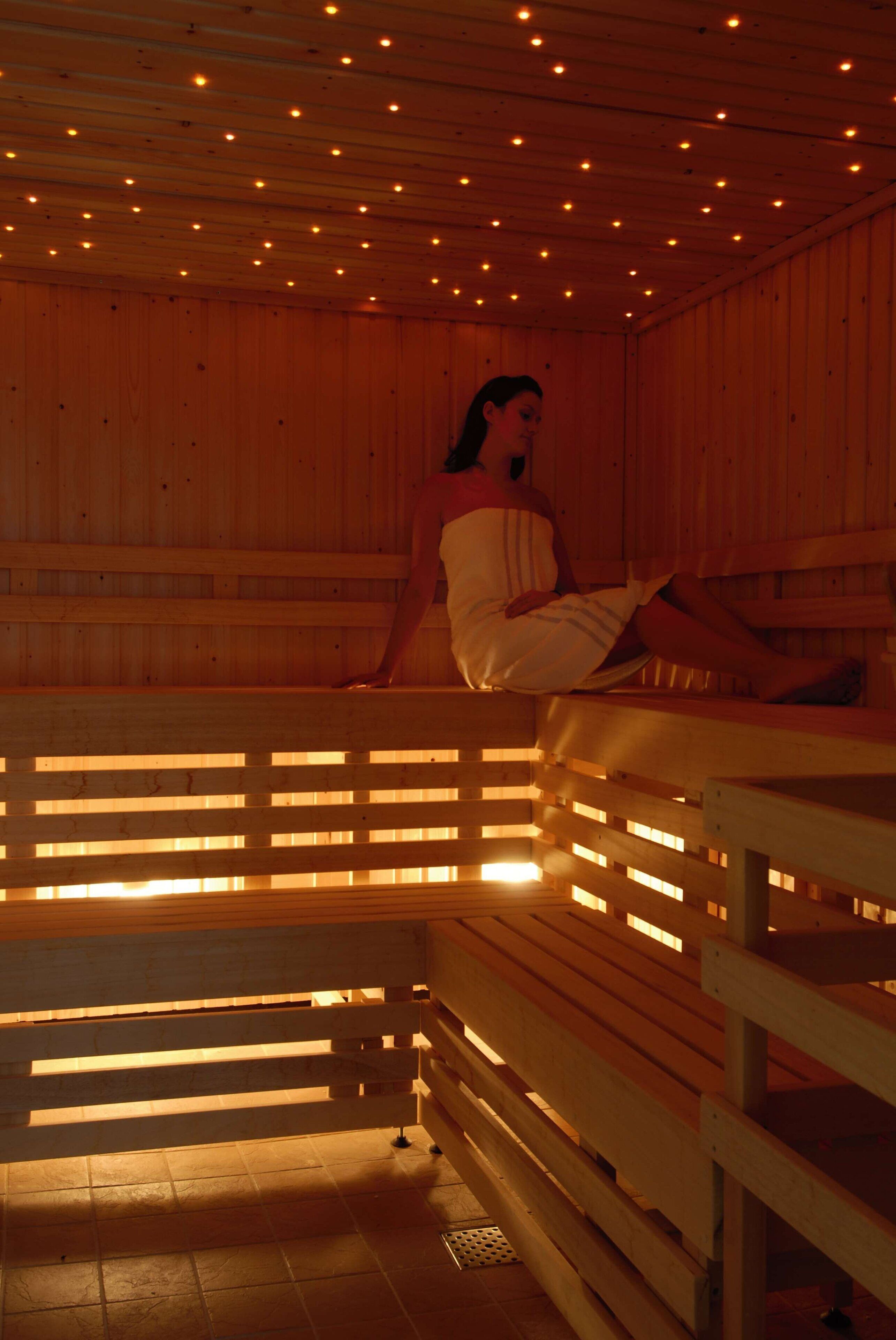 Una sauna con bancos de madera y una persona sentada en uno.