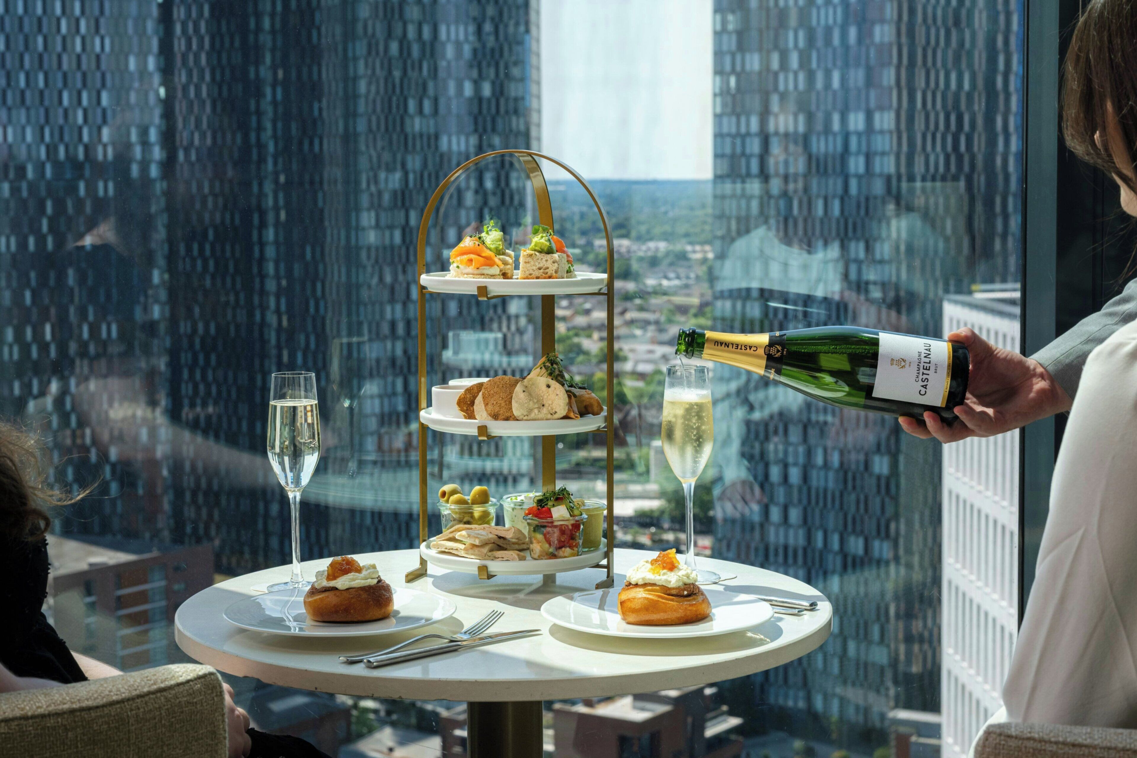 A multi-tiered dessert stand with various pastries and a bottle of champagne being poured into a glass.