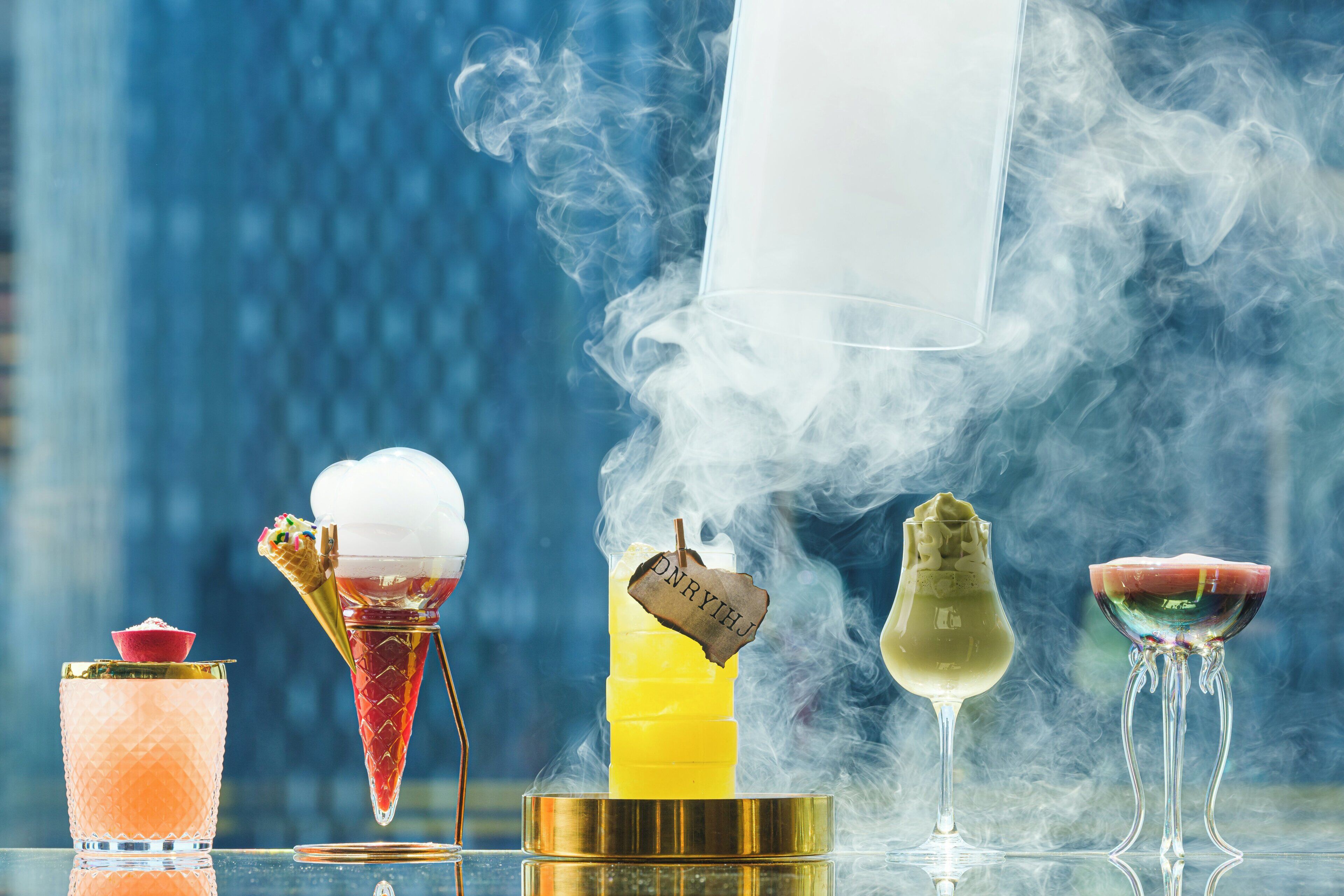 A variety of drinks in unique glassware, including an ice cream cone, a tall glass, a cocktail, and a wine glass.