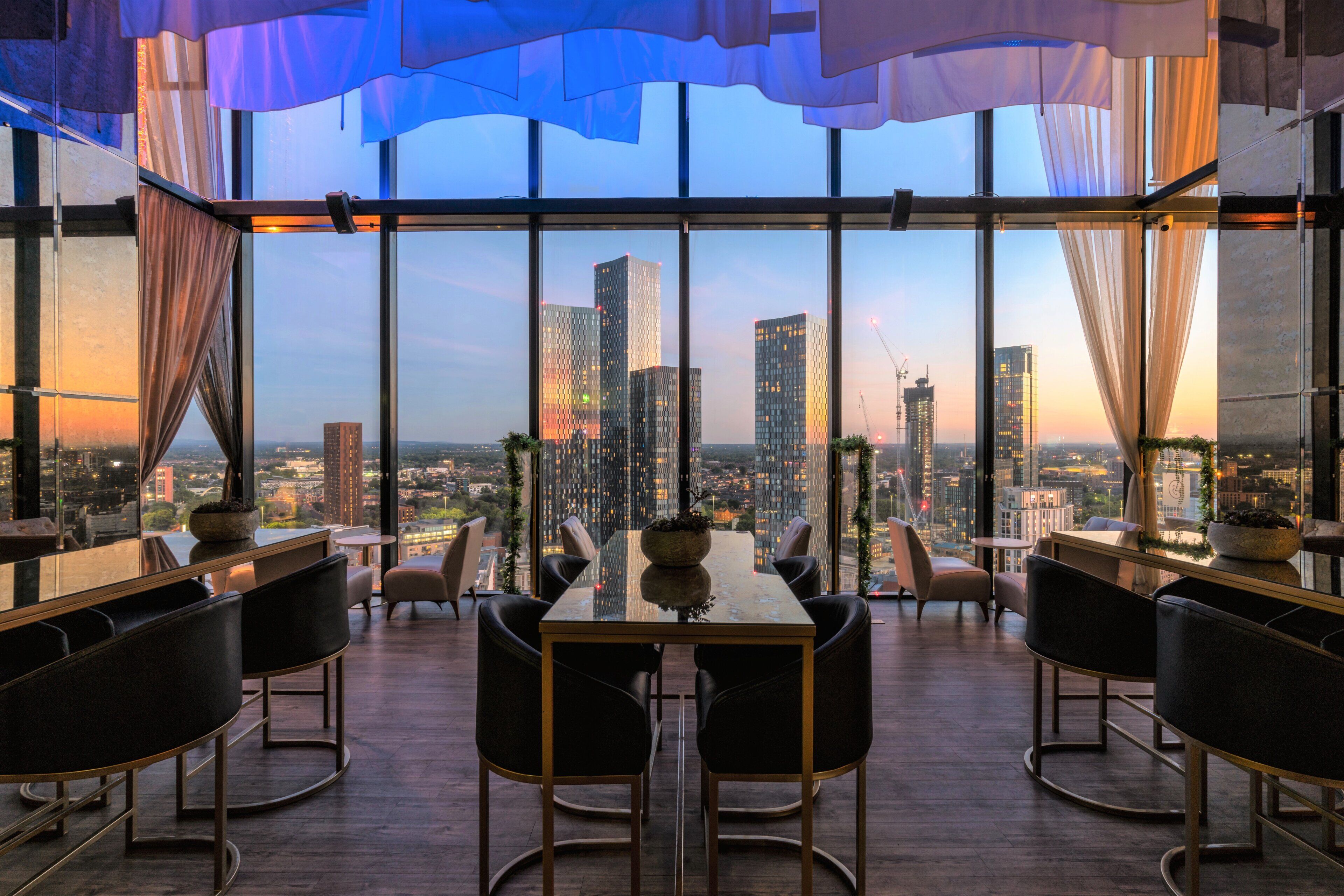 A modern dining area with a city view, large windows, and contemporary furniture.