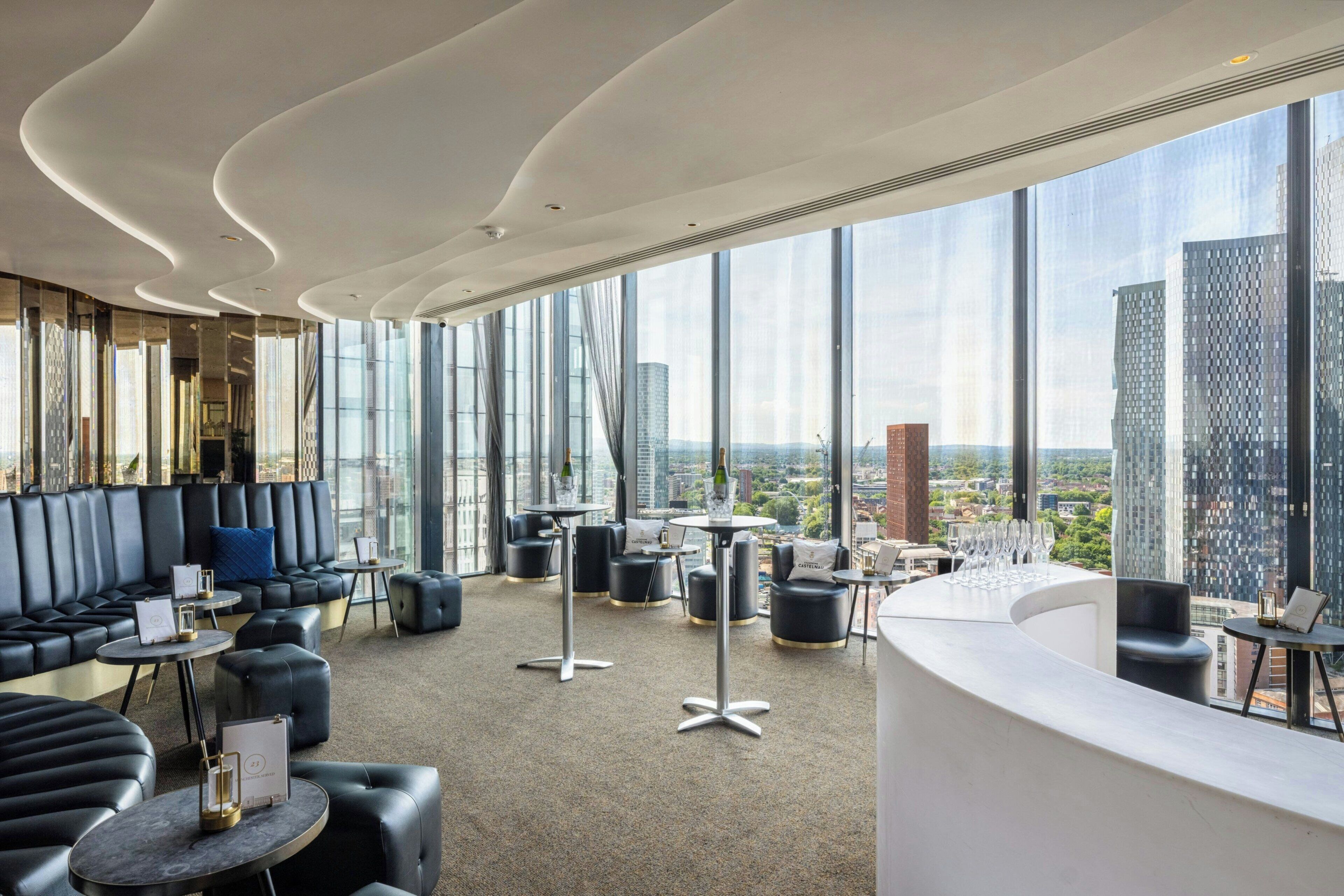 A modern lounge area with leather seating, round tables, and a city view through large windows.