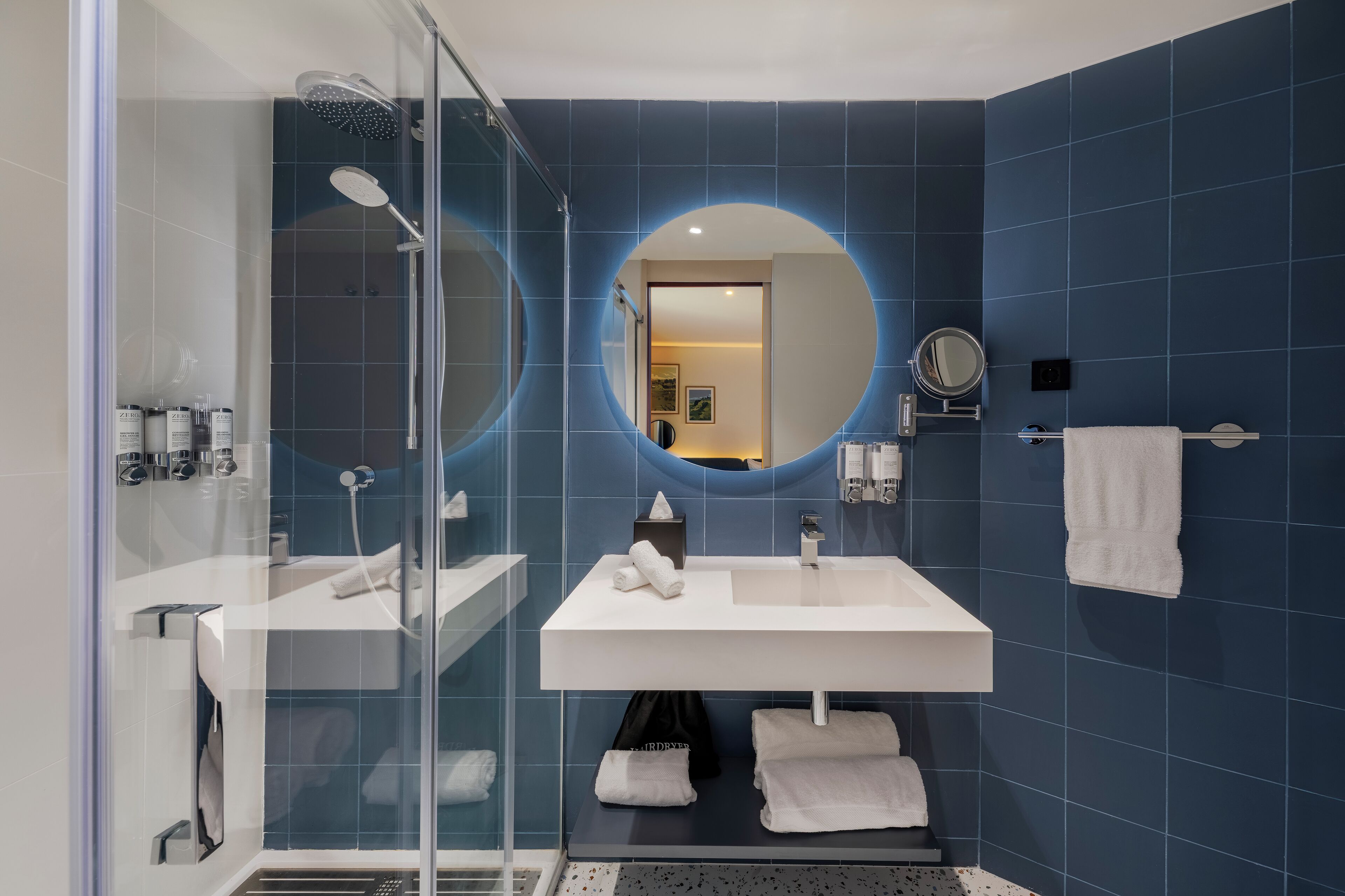 Une salle de bain moderne avec une douche à parois de verre, deux lavabos et un grand miroir.