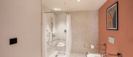 Un baño moderno con ducha, inodoro y barandilla para accesibilidad.