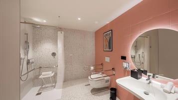 Een moderne badkamer met douche, toilet en wastafel, met een spikkeltjes vloer en roze wanden.