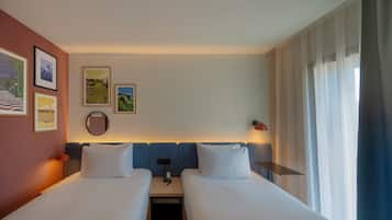 Een hotelkamer met twee bedden, een nachtkastje, een lamp en kunst aan de muur.