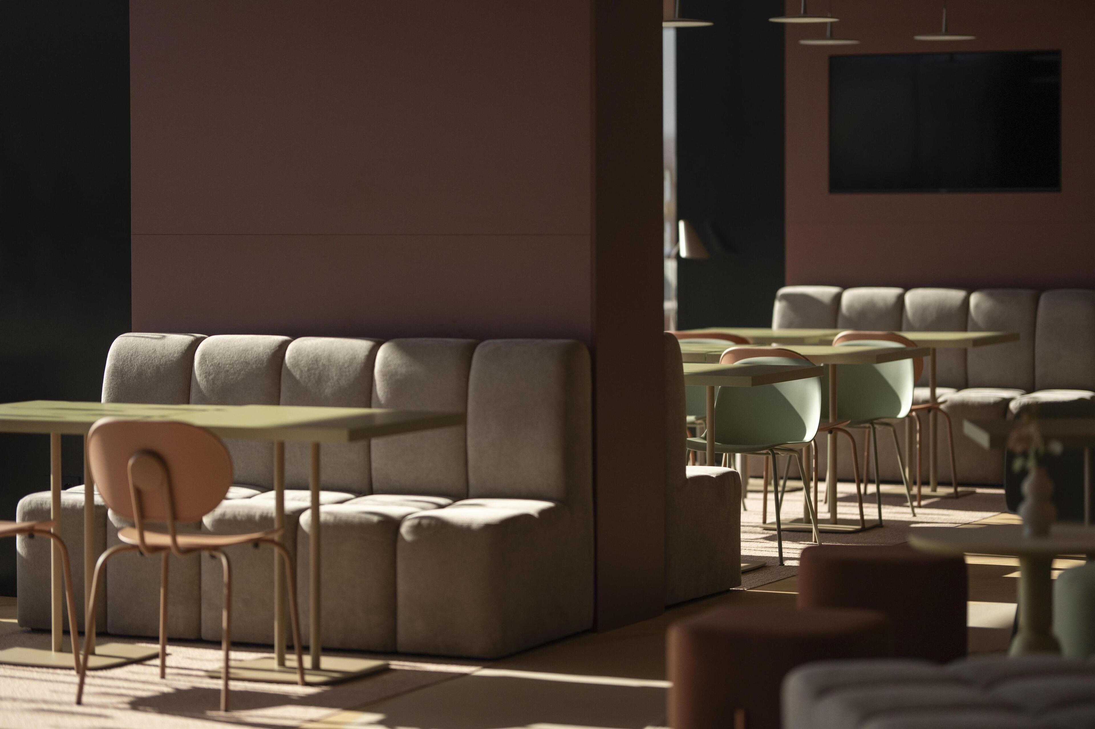 Un interior moderno con arreglos de asientos y mesas, que presenta un diseño minimalista y una paleta de colores neutros.