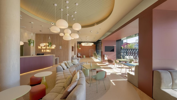 A modern lounge area with a reception desk, seating arrangements, and a dining area. - Hampton By Hilton Alicante Airport (Elche)
