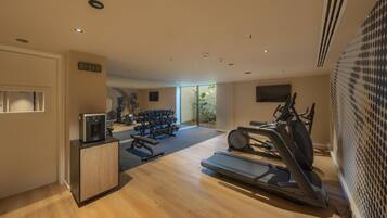 A modern gym with a treadmill, elliptical, and dumbbells.
