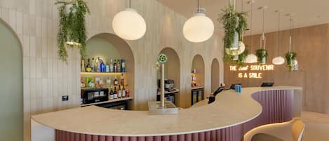 Eine moderne Bar mit einer gebogenen Theke, mehreren hängenden Leuchten und einer mit Flaschen bestückten Bar.