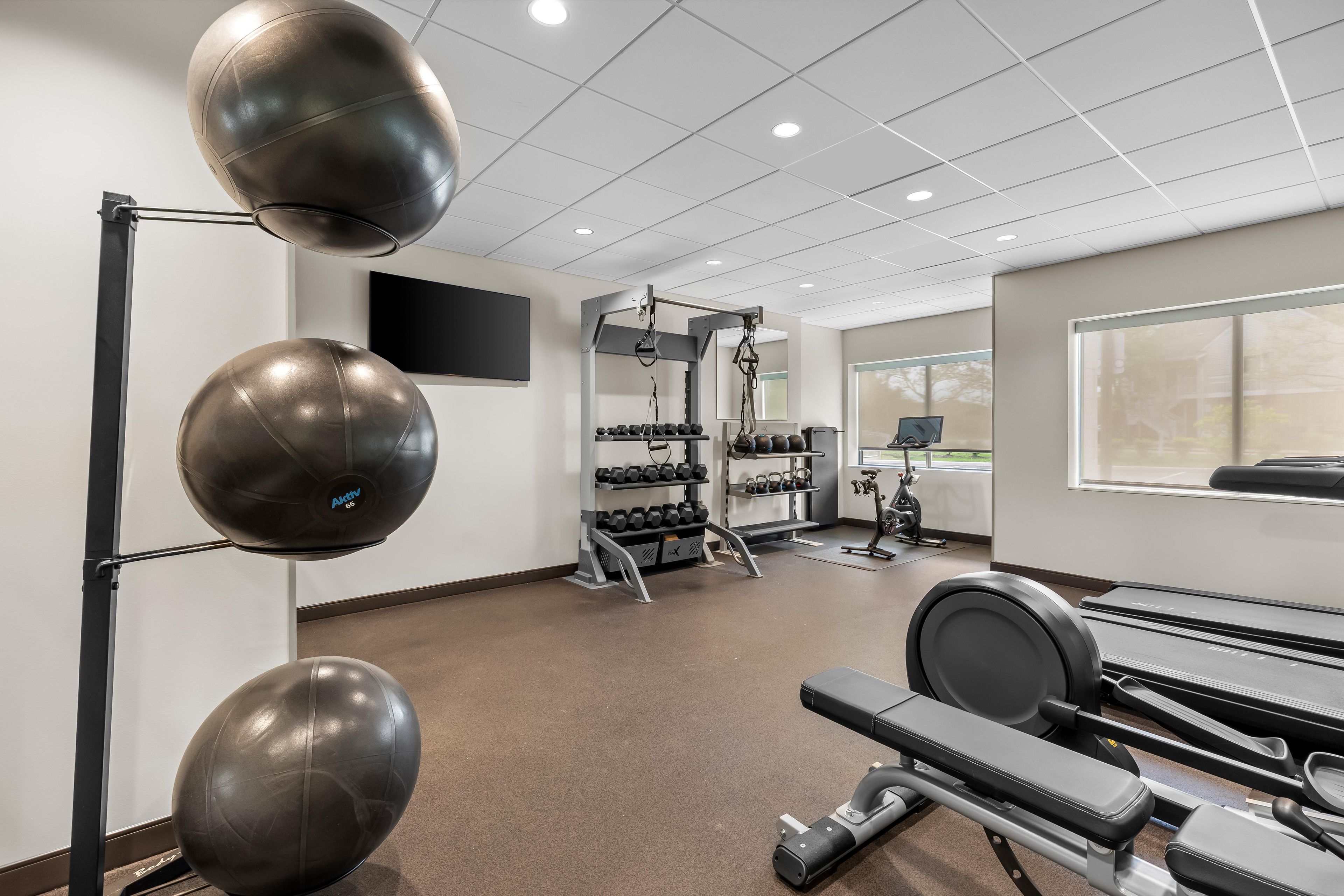 Un gimnasio con equipo de ejercicio, una cinta de correr y una televisión instalada en la pared.