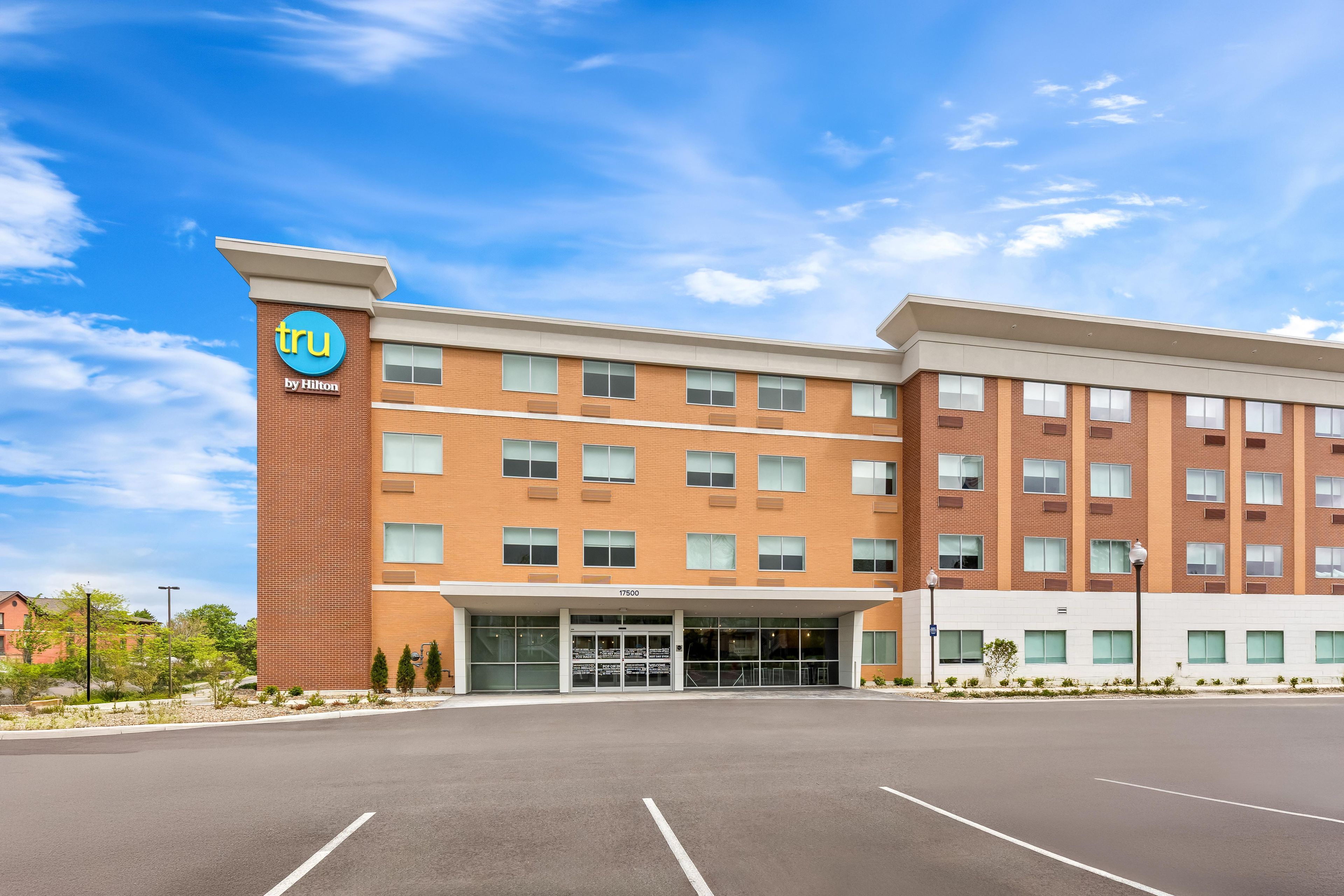 A hotel with a modern brick facade, a clear sky, and a parking lot.