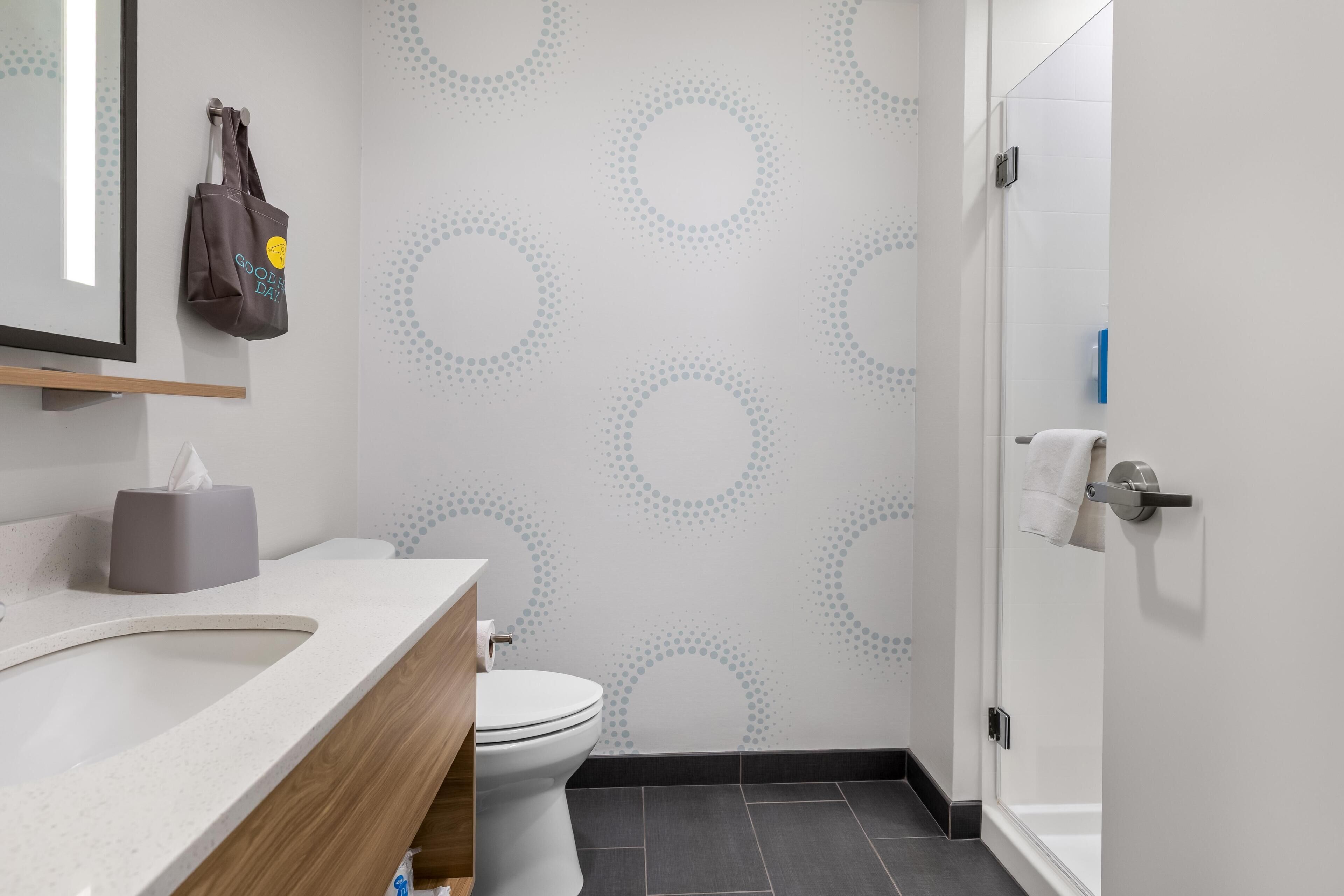 A bathroom with a toilet, a sink, a mirror, a towel rack, and a shower door.
