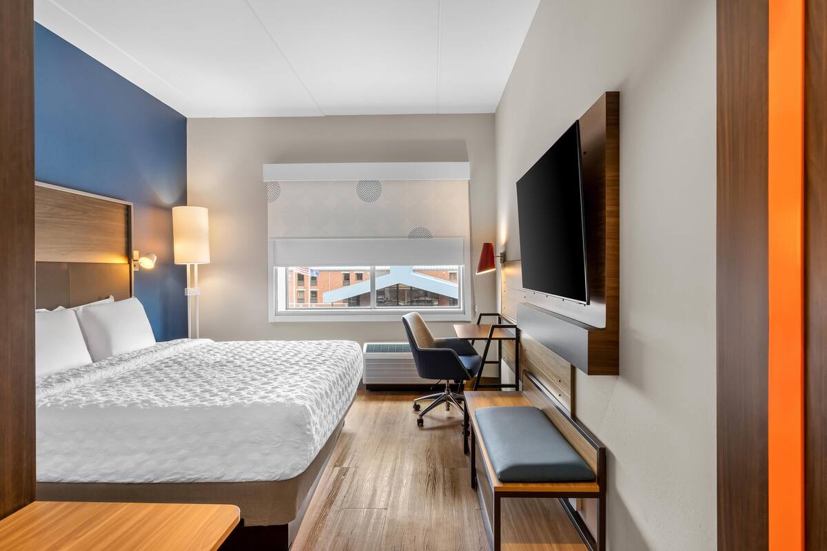Ein Hotelzimmer mit Bett, Schreibtisch, Stuhl, Fernseher und einem Fenster mit Blick.