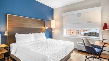 A hotel room with a large bed, bedside lamps, a desk, and a window with a view.