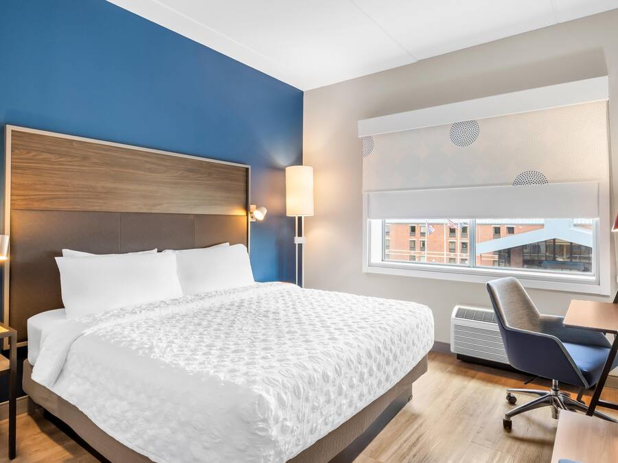 A hotel room with a large bed, bedside lamps, a desk, and a window with a view.