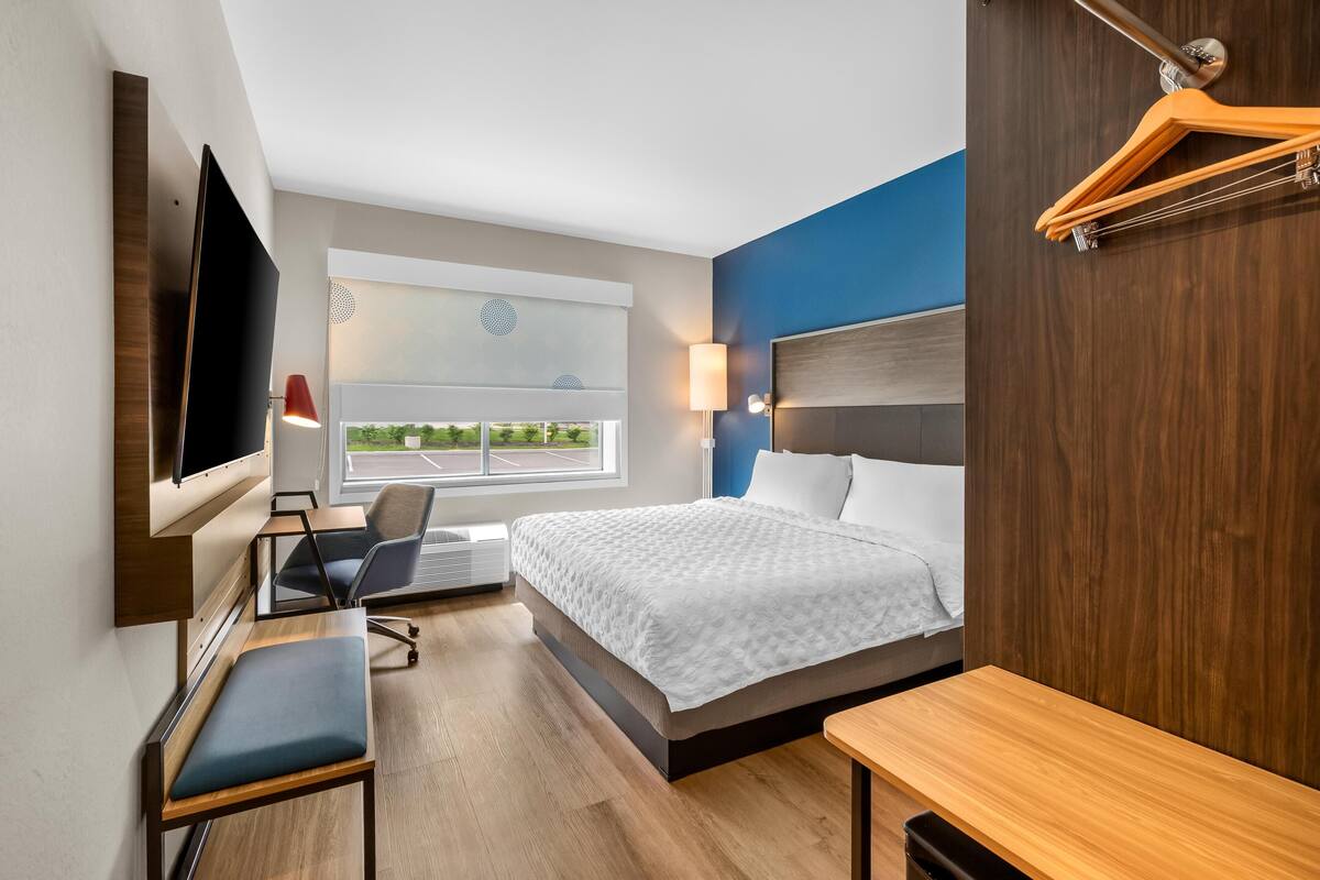 Ein Hotelzimmer mit Bett, Schreibtisch, Stuhl, Fernseher und Fenster mit Blick.