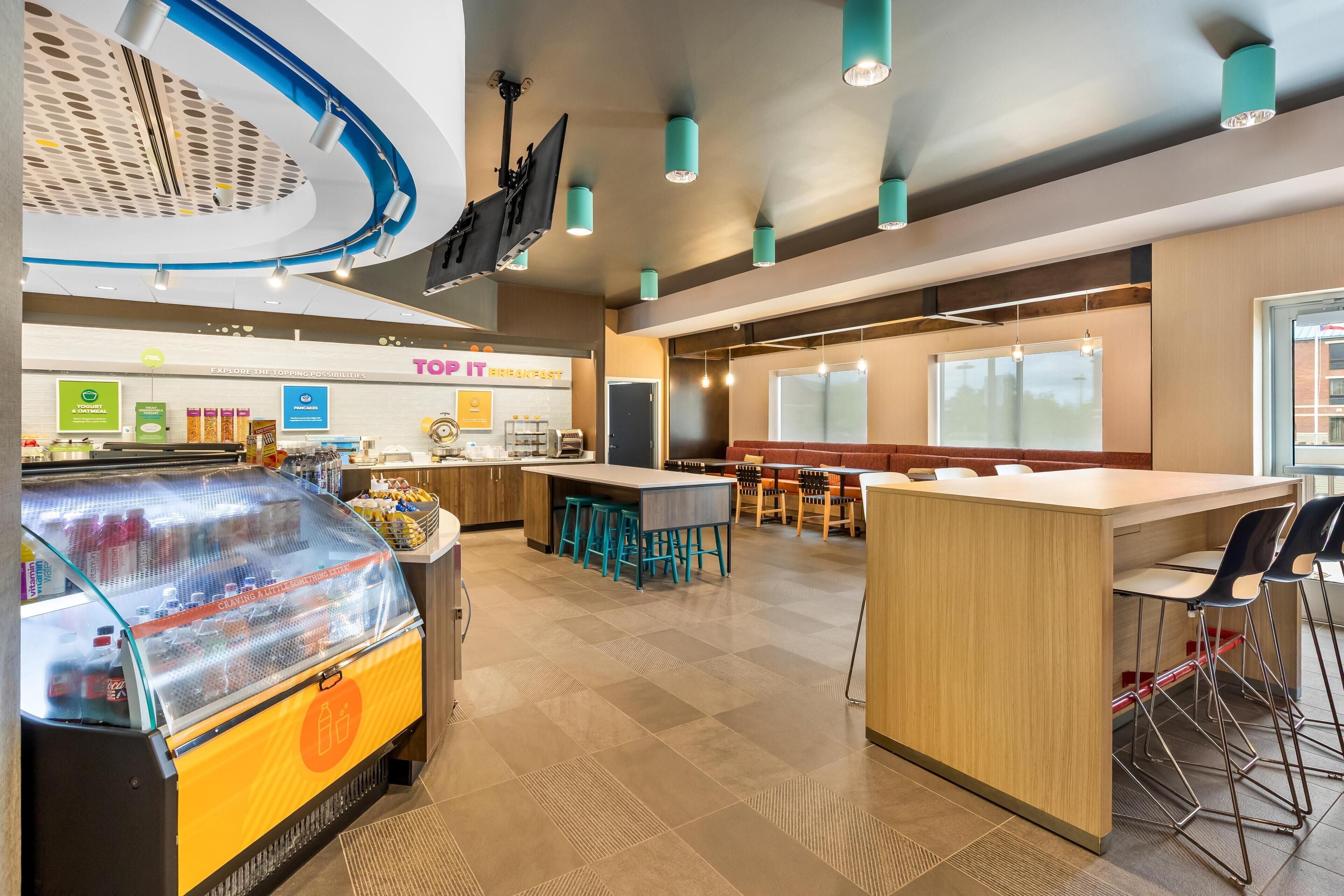 Een modern restaurant met een centraal eiland, een bar en een vitrine voor eten.