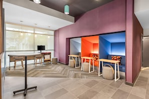 Un intérieur moderne avec une table ronde, des chaises, un canapé et un petit téléviseur.