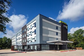A modern hotel building with a flat roof, large windows, and a sign indicating it is a Hilton hotel. - Home2 Suites By Hilton Tyler (Tyler)