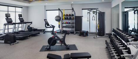 A gym with treadmills, a stationary bike, and weightlifting equipment.