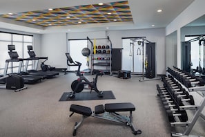 A gym with treadmills, a stationary bike, and weightlifting equipment. - Home2 Suites By Hilton Tyler (Tyler)