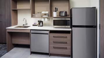 A compact kitchen with a built-in dishwasher, a microwave, and a refrigerator.