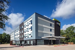 A modern hotel building with a flat roof, large windows, and a sign indicating it is a Hilton hotel. - Home2 Suites By Hilton Tyler (Tyler)