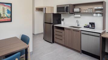 A compact kitchenette with a refrigerator, microwave, sink, and coffee maker.