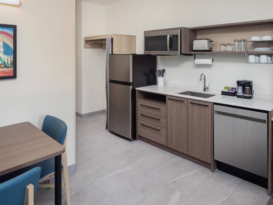 A compact kitchenette with a refrigerator, microwave, sink, and coffee maker.