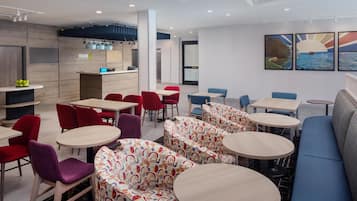 A modern hotel lobby with seating areas, a reception desk, and artwork on the walls.