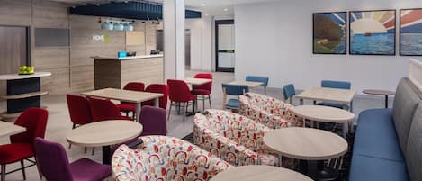 A modern hotel lobby with seating areas, a reception desk, and artwork on the walls.