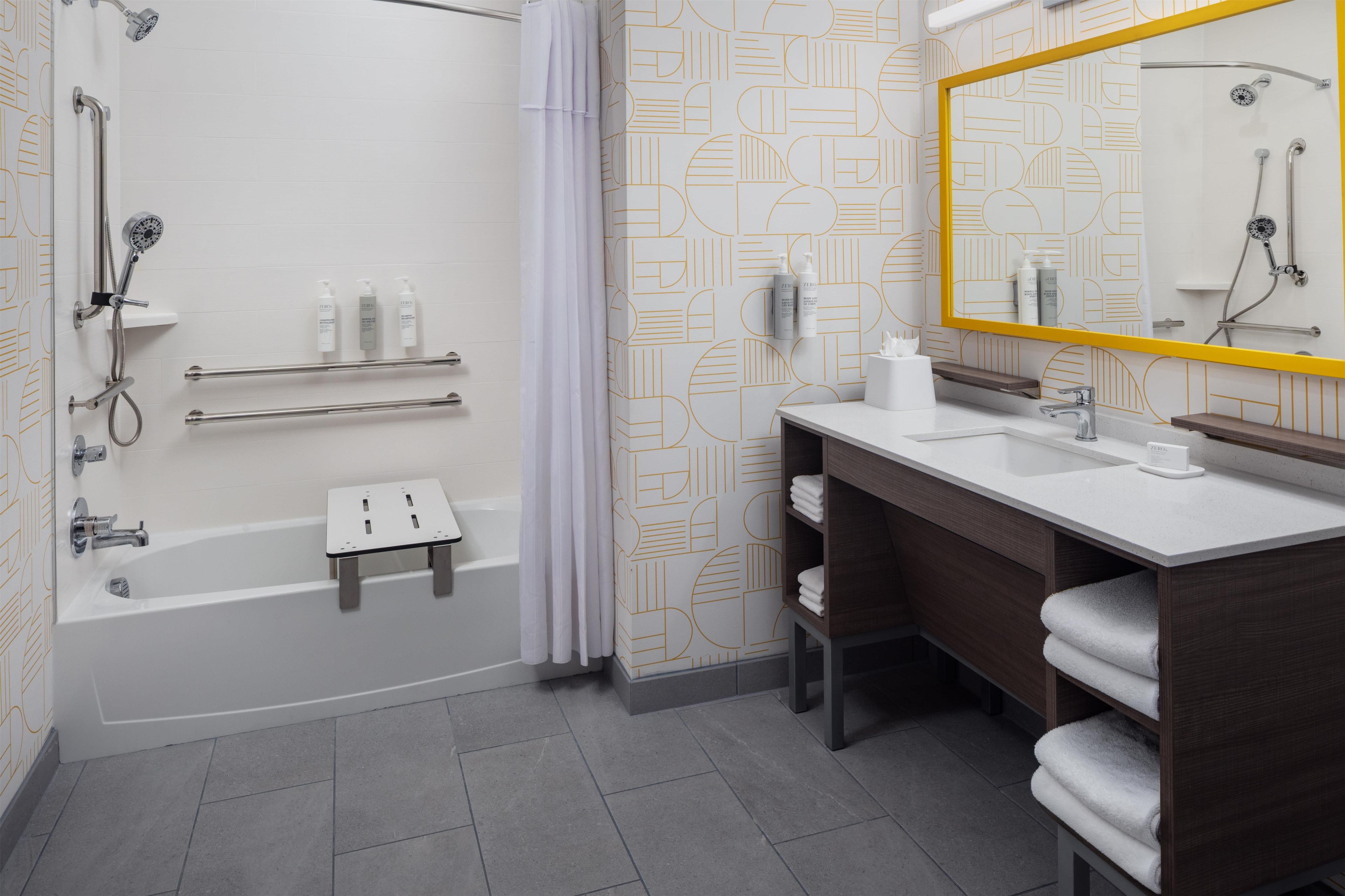 A modern bathroom with a walk-in shower, a bathtub, a vanity with a mirror, and a towel rack.