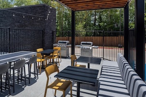 Un patio exterior con pared de piedra, una parrilla y asientos.