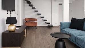 A modern living room with a sofa, a coffee table, a TV, a lamp, and a staircase. - Maison Michela Sorrento (Sorrento)