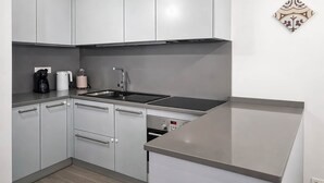 A modern kitchen with white cabinets, a stainless steel sink, a built-in oven, and a countertop. - Maison Michela Sorrento (Sorrento)