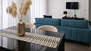 A modern living room with a sofa, a TV, a table with a vase, and a window with curtains. - Maison Michela Sorrento (Sorrento)