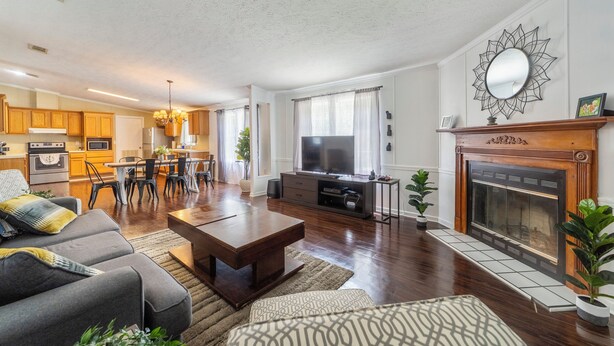 A spacious living room with a fireplace, a dining area, and a kitchen in the background. - Raceway Retreat, just 12 miles from UF/downtown, relaxing country getaway! (Gainesville)