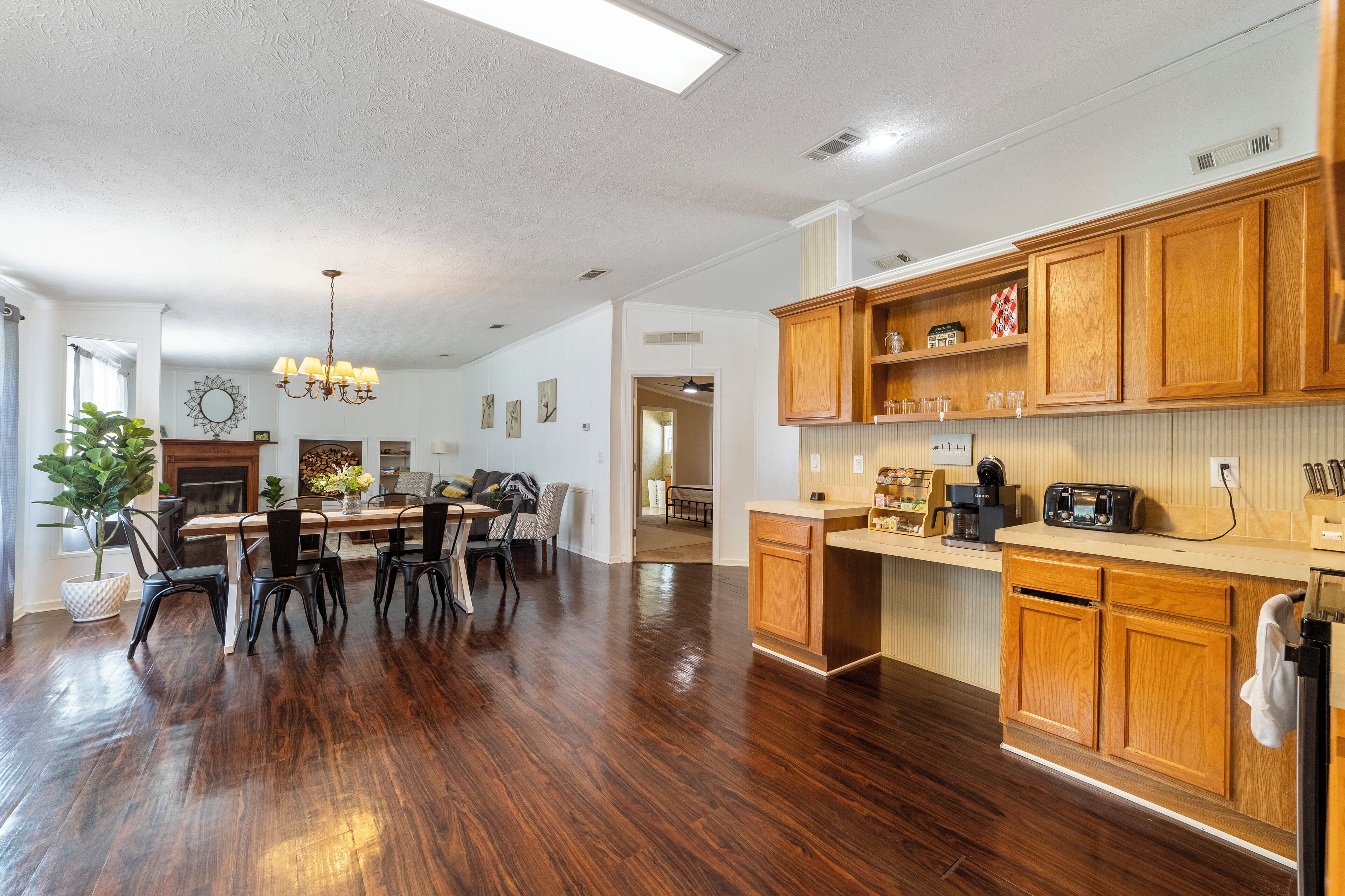A spacious kitchen with wooden cabinets, a dining area with chairs, and a chandelier.