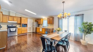 A spacious kitchen with wooden cabinets, a dining table with chairs, and a chandelier. - Raceway Retreat, just 12 miles from UF/downtown, relaxing country getaway! (Gainesville)