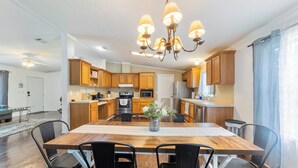 A spacious kitchen with wooden cabinets, a central island, and a chandelier. - Raceway Retreat, just 12 miles from UF/downtown, relaxing country getaway! (Gainesville)
