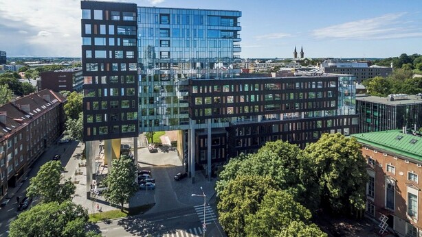 A modern building with a glass facade and a unique architectural design, surrounded by trees and other buildings. - Luxury Apartment in Prime Area (Tallinn)