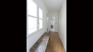 A narrow hallway with wooden flooring and large windows on one side. - SURROUNDED BY THE BEST BOUTIQUES, GALLERIES, CAFÉS, AND RESTAURANTS – LE MARAIS (Paris)