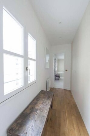 Un couloir étroit, doté d’un plancher en bois et de grandes fenêtres sur un de ses côtés.