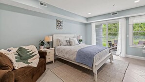 Ein Schlafzimmer mit Bett, Nachttischen, einem Schminktisch und einem Deckenventilator. Ein Fenster bietet einen Ausblick.