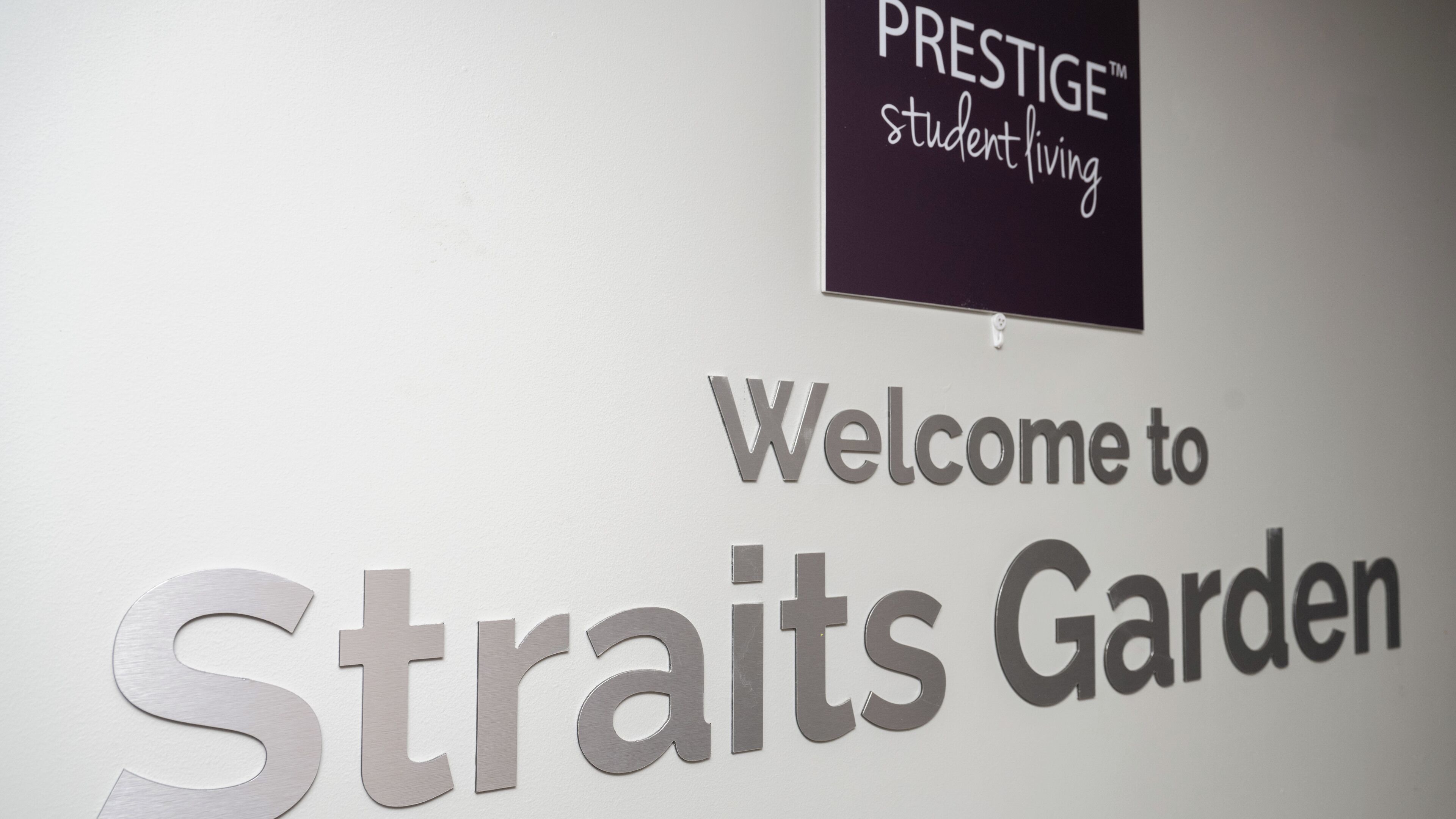 A welcome sign for Straits Garden with a Prestige student living sign above it.