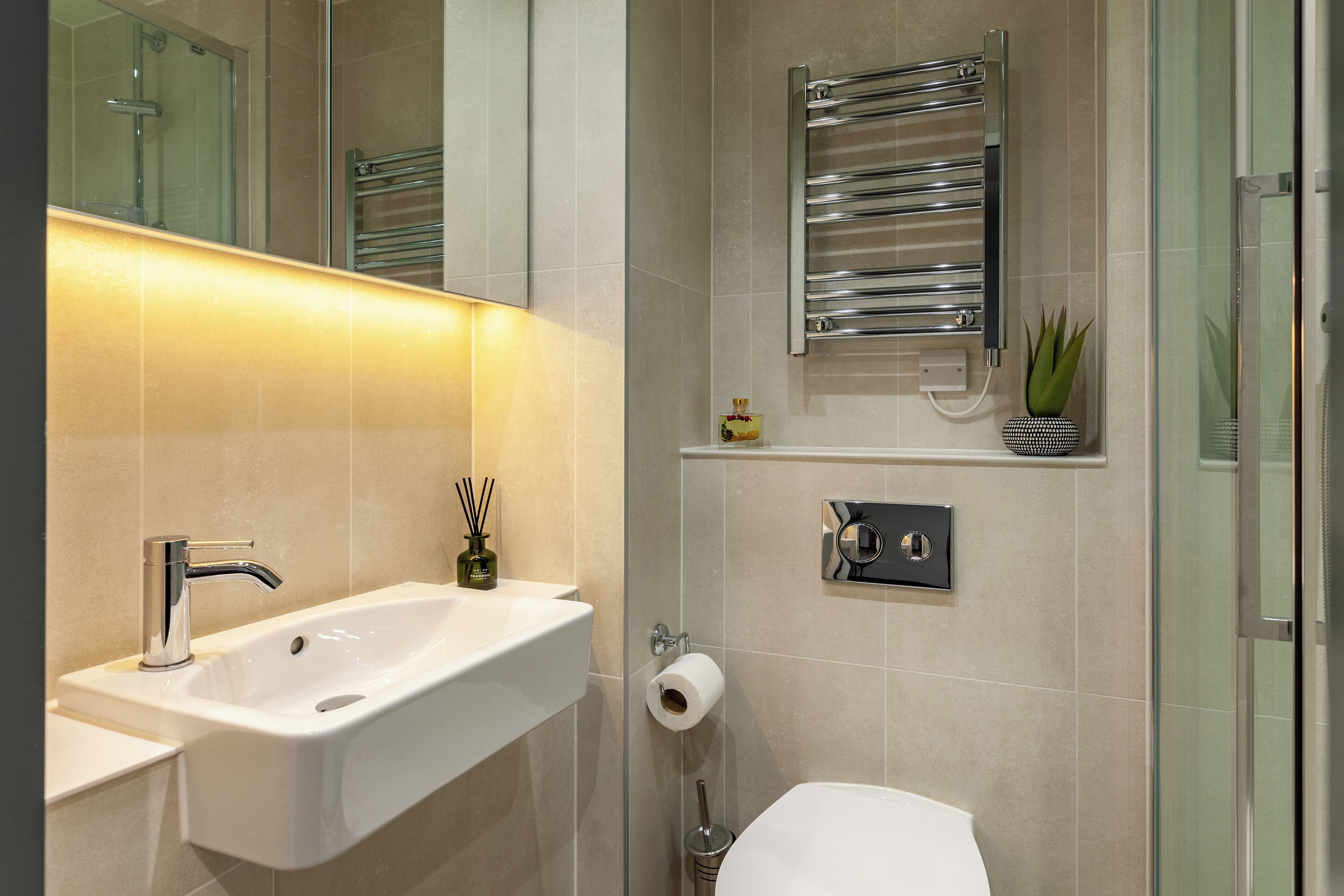 A modern bathroom with a white sink, chrome faucet, and a glass shower enclosure.