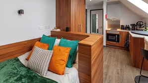 Ein kleines Zimmer mit Bett, einer Küchenzeile und Blick nach außen.
