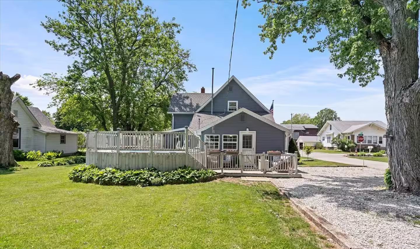 A residential property with a fenced deck, a well-maintained lawn, and a two-story house with a gabled roof.