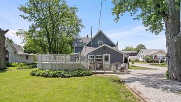 A residential property with a fenced deck, a well-maintained lawn, and a two-story house with a gabled roof.