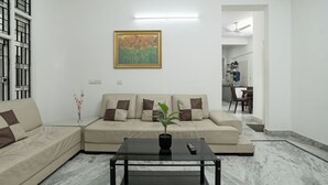 A living room with a sofa, a coffee table with a plant, and a painting on the wall.